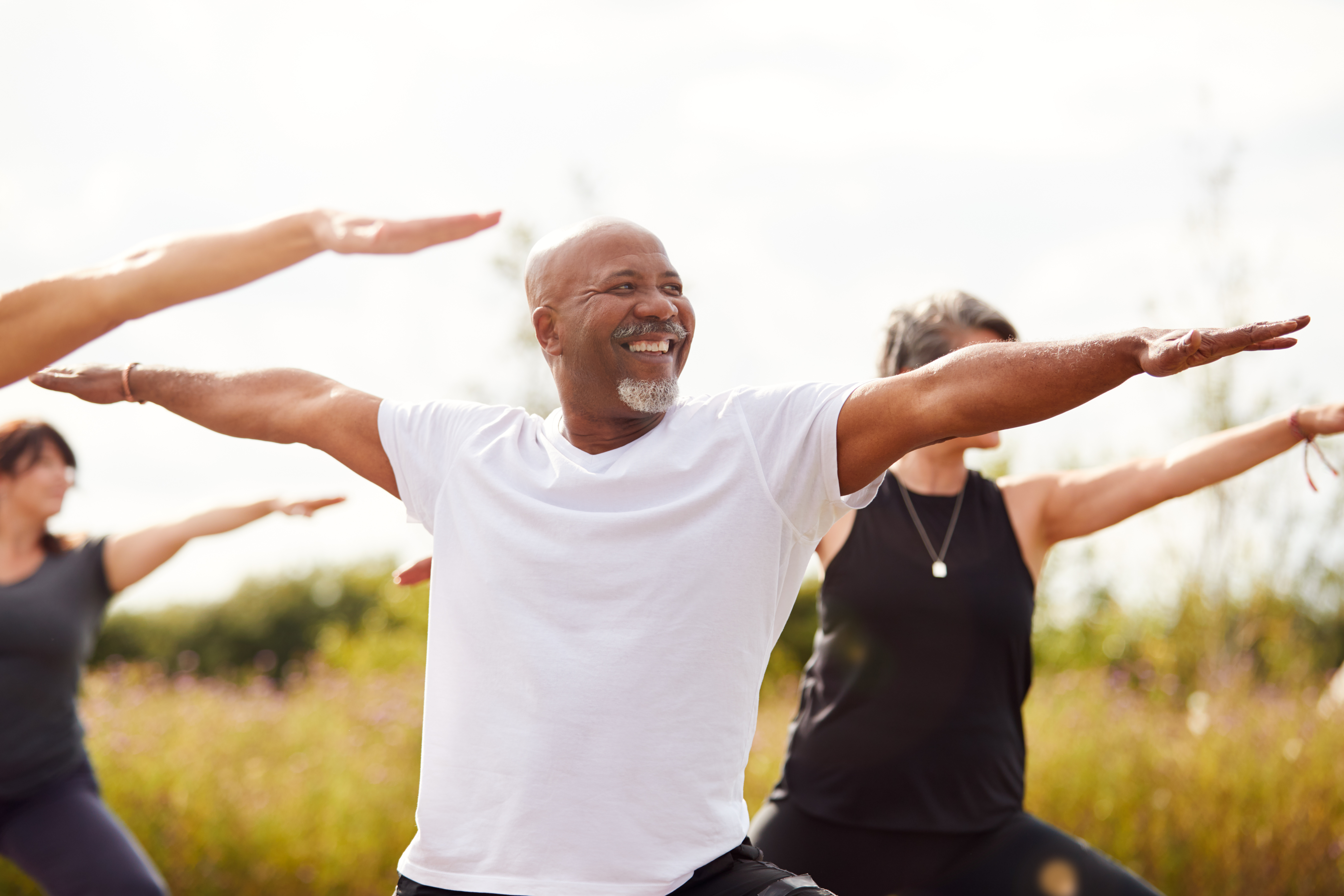 Group of middle aged people practicing yoga in the evening outdoors